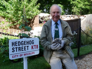 Pat Morris holding a hedgehog in front of the garden